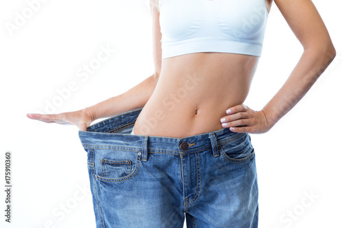 Beautiful young woman wearing big jeans over white background.