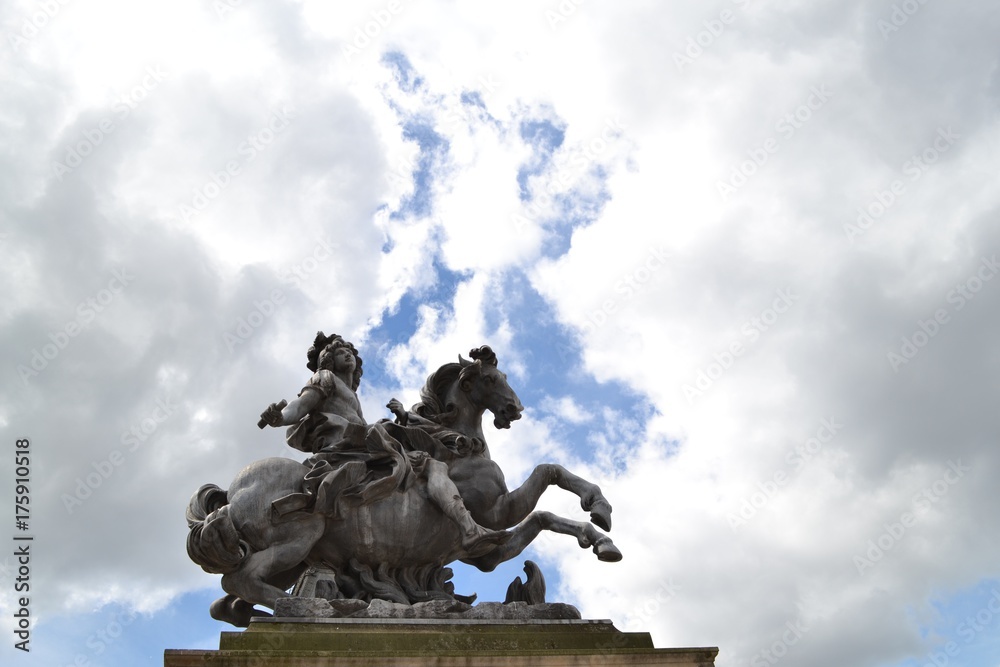 Dramatic view of King Louis XIV Statue, against cloudy sky, in Paris, in 1st Arrondissement, near Louvre Museum, France