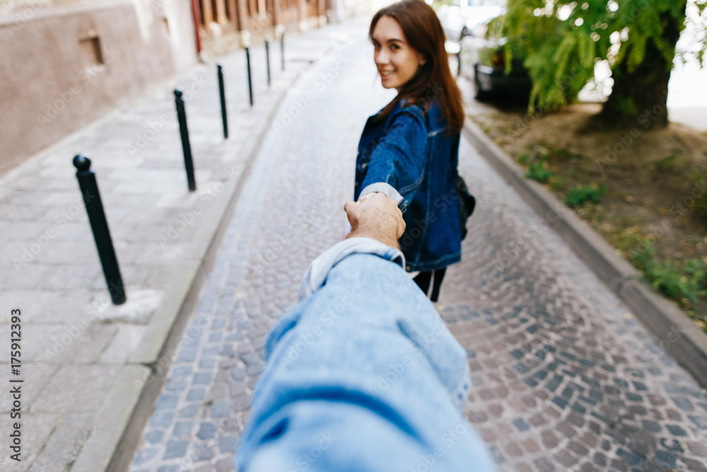 Look from behind at young woman holding man's hand in 'Follow me' pose Look from behind at young woman holding man's hand in 'Follow me' pose