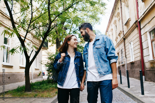 Woman holds man's hand walking with him on the old European city