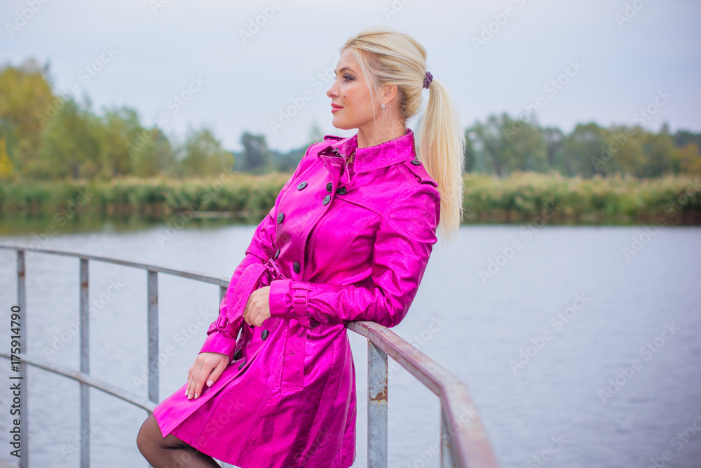 Sweet and cute woman in a pink coat walks in the city park. Bright and interesting elements of the look in the modern style for autumn and spring