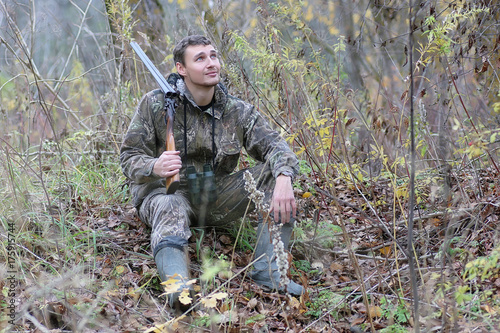 Man in camouflage and with guns in a forest belt on a spring hunt
