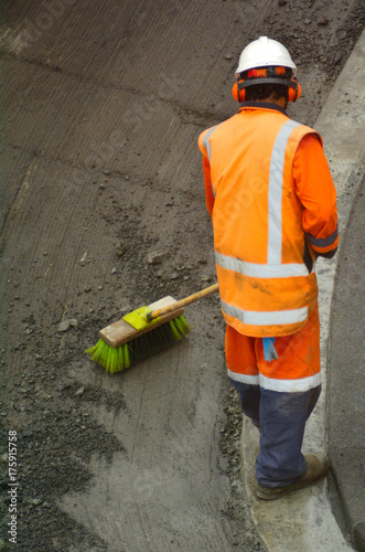Road worker brooming remains of asphalt