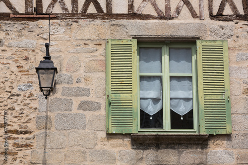SAINT-LEONARD-DE-NOBLAT, FRANCE - 22 JULY, 2017: Detail of the facade of a half-timbered house, with a window with shutters and an old streetlight.