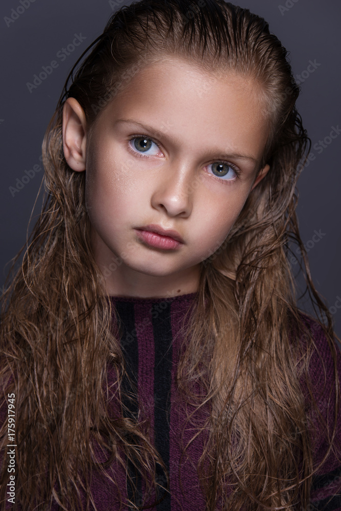 Closeup portrait of cute little girl with dark hair in studio over grey background. Closeup portrait of cute little girl with dark hair in studio over grey background.