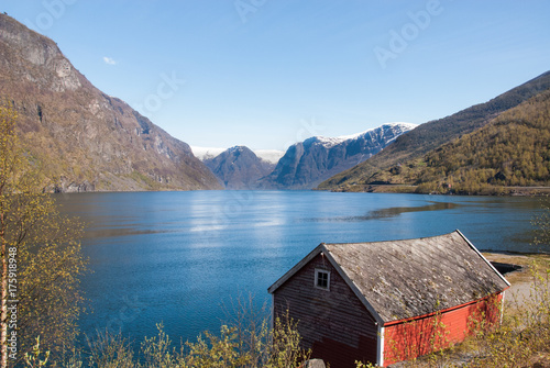 Fjord with mountains as backdrop with roof of small hut in foreground