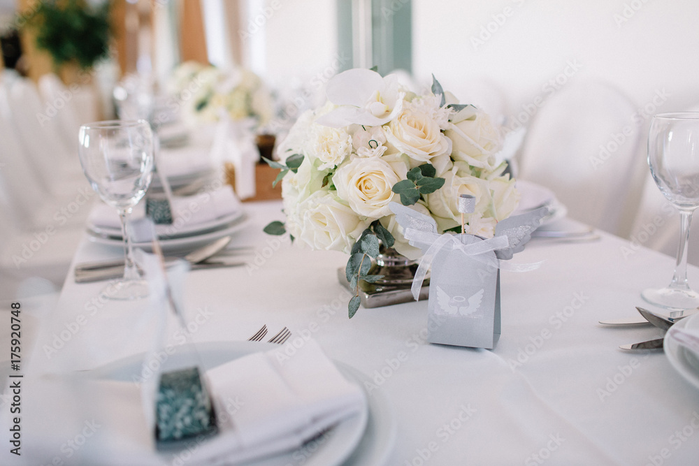 Bouquet of white roses stands on white dinner table Bouquet of white roses stands on white dinner table