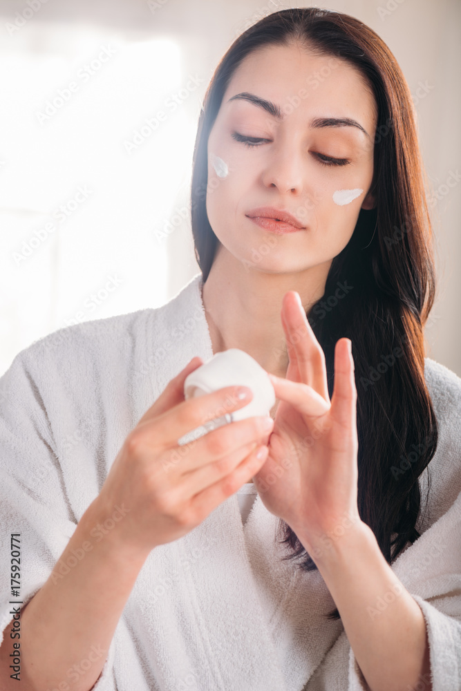 woman in bathrobe applying face woman in bathrobe applying face