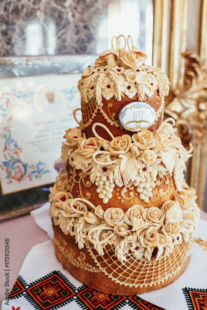 Layered wedding bread with flowers stands on steel dish Layered wedding bread with flowers stands on steel dish