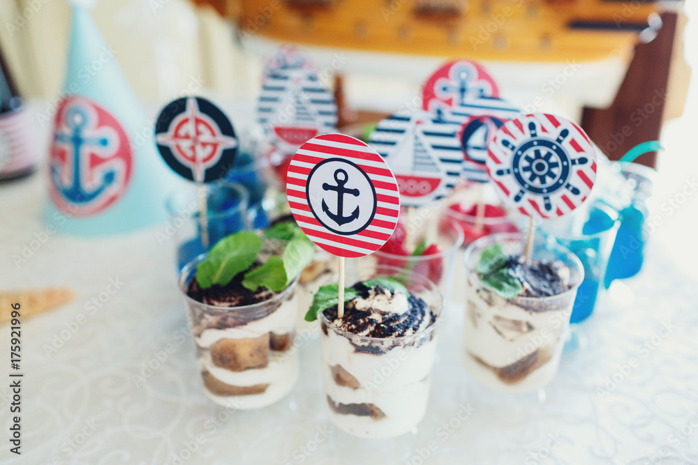 Glasses with tiramissu and colorful berries decorated with anchors, yachts and other marine theme