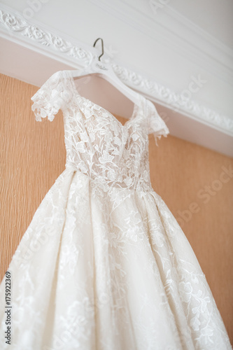 Wedding dress hangs over large bed in the room