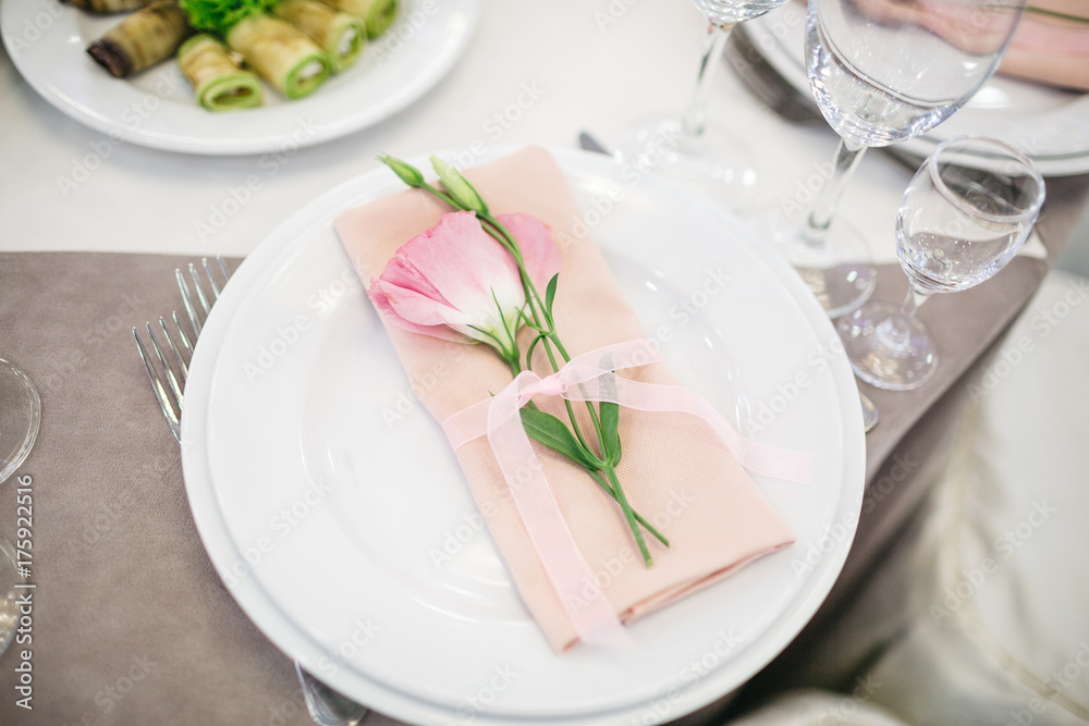 Pink tulip lies on pink serviette on a dinner plate Pink tulip lies on pink serviette on a dinner plate