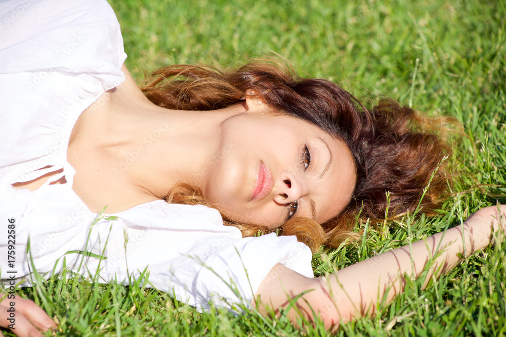 Beautiful woman intense expression looking camera smiling lying in park closeup Beautiful woman intense expression looking camera smiling lying in park closeup