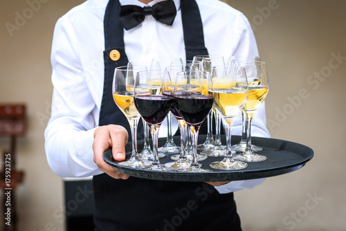 Fotografie Professional waiter in black uniform serving red and white wine.