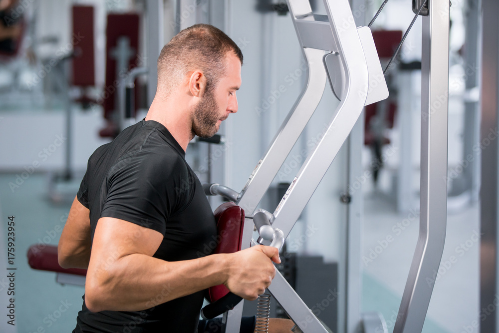 muscular man working on fitness machine at the gym muscular man working on fitness machine at the gym