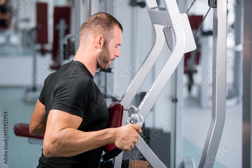 muscular man working on fitness machine at the gym
