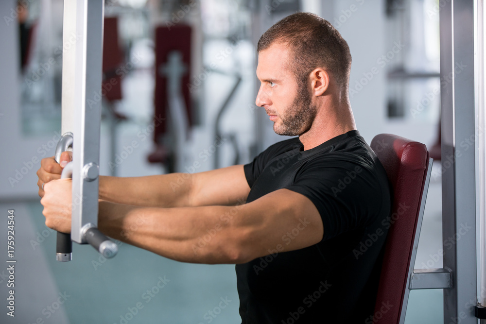 muscular man working on fitness machine at the gym