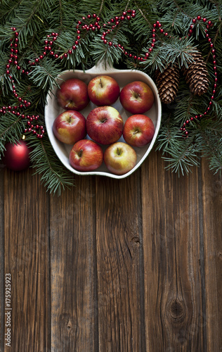 Christmas decor with apples and fir0tree branches on rustic wooden background. Top view, background
