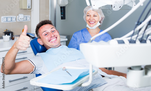 Portrait of satisfied man visiting dentist giving thumbs up