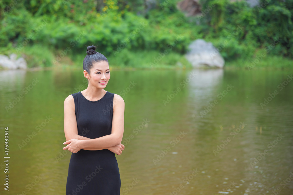 Beautiful asian girl in black dress smiling near by the river