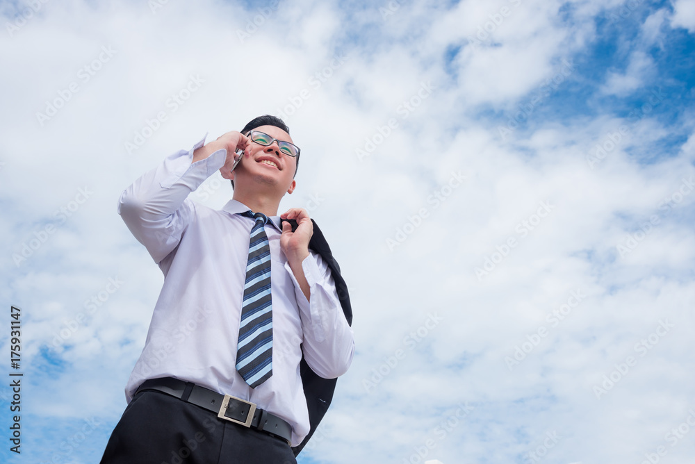 Young asian businessman using mobile phone with sky background Young asian businessman using mobile phone with sky background