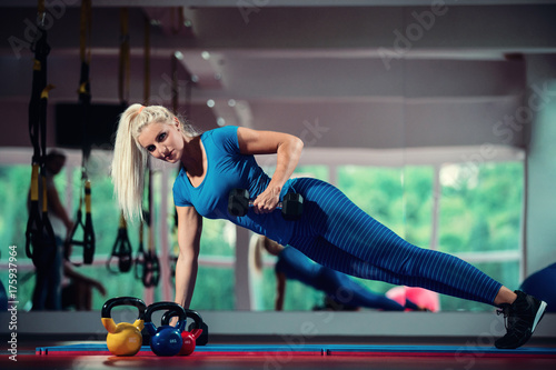 Fitness girl doing dumbbells plank row exercise