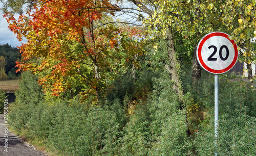 Round road speed limit sign at twenty kilometers per hour on the autumn rural road