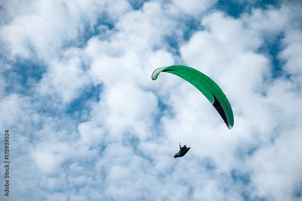 Paraglider flying in the blue sky against the background of clouds. Paragliding in the sky on a sunny day. Paraglider flying in the blue sky against the background of clouds. Paragliding in the sky on a sunny day.