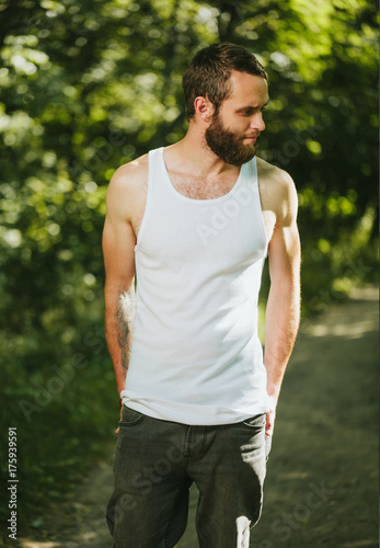Hipster handsome male model with beard wearing white blank A-shirt with space for your logo or design in casual urban style