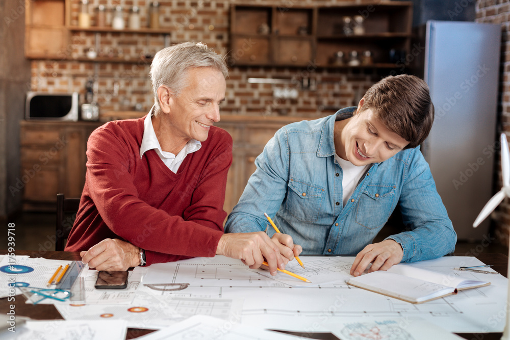 Smiling man pointing at problematic place in colleagues blueprint Smiling man pointing at problematic place in colleagues blueprint