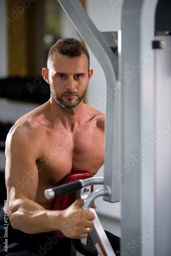 muscular man working on fitness machine at the gym