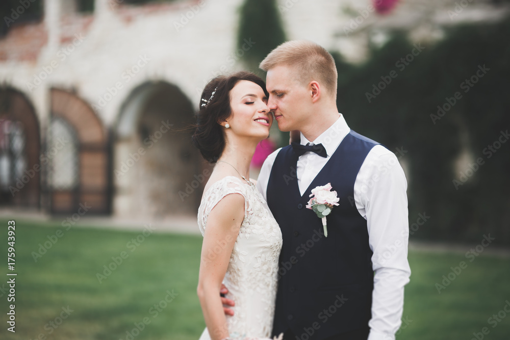 Lovely happy wedding couple, bride with long white dress posing in beautiful city Lovely happy wedding couple, bride with long white dress posing in beautiful city