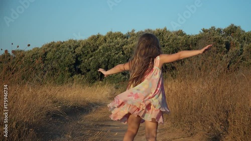 Little girl jumping and running on country road.