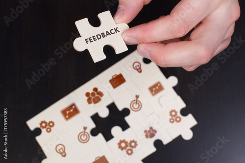 The concept of business, technology, the Internet and the network. A young businessman collects a puzzle with the proper inscription: Feedback