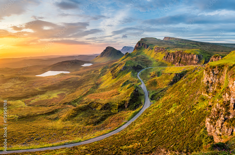 Fototapeta premium Długa kręta droga w Quiraing na wyspie Skye z pięknym wibrującym niebem wschód słońca.