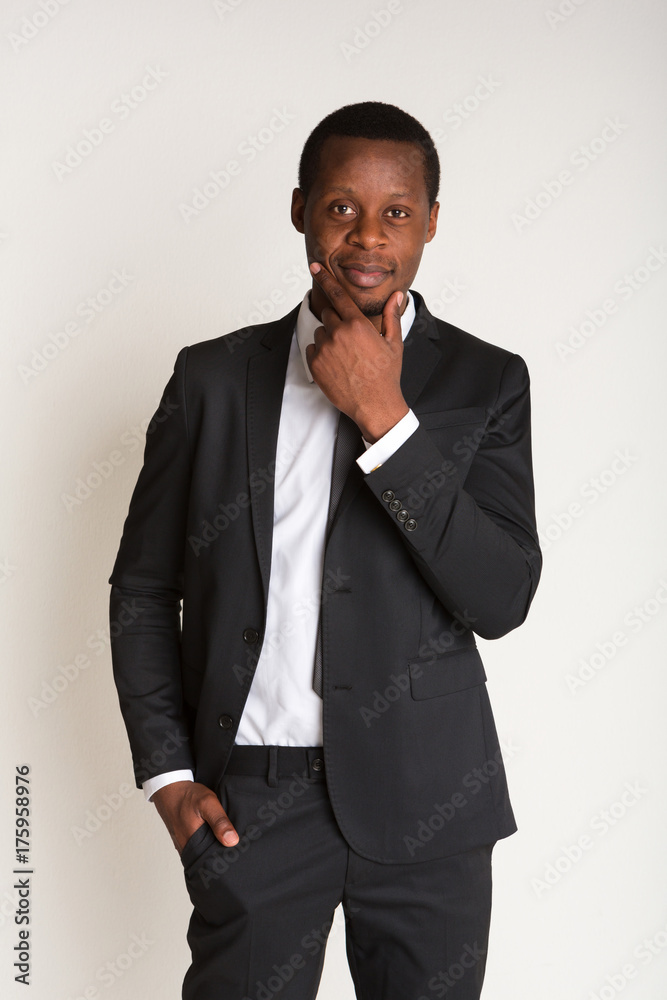 Powerful black businessman standing in suit, straightens tie Powerful black businessman standing in suit, straightens tie