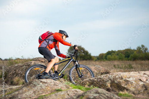 Cyclist in Red Riding the Bike on the Rocky Trail at Sunset. Extreme Sport and Enduro Biking Concept.