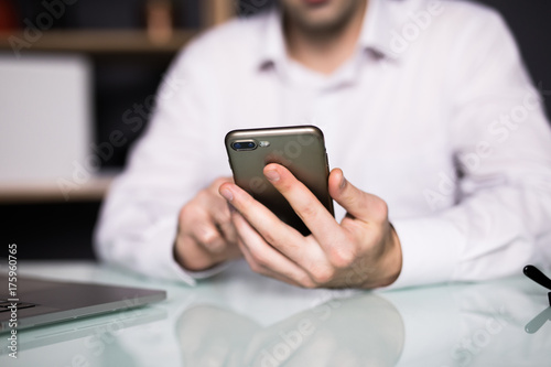 businessman using smart phone in office, hand close up