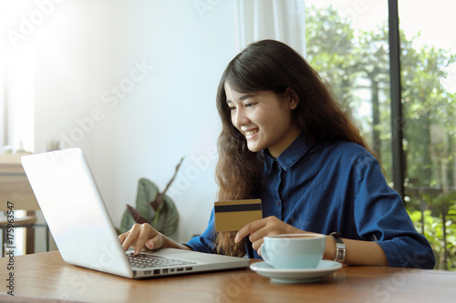Young asian woman using computer with a credit card to shopping online in coffee shop.