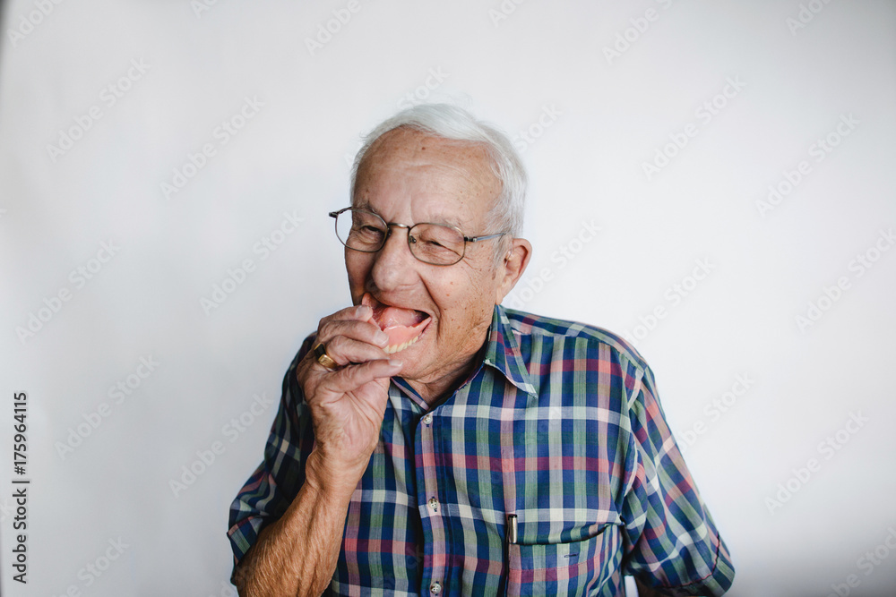 Playful senior man removing dentures and laughing Playful senior man removing dentures and laughing
