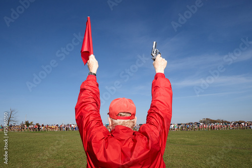 Fotografia Man holding up a starter gun and flag