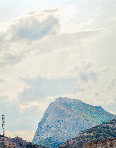 Beautiful landscape with green mountains and magnificent cloudy sky in sunset. Exploring Crimea, Sudak. Dramatic sky over rocks. Mountains with evening light.