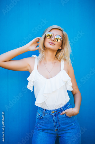 Blonde with white shirt and sunglasses on a blue background © F8  \ Suport Ukraine