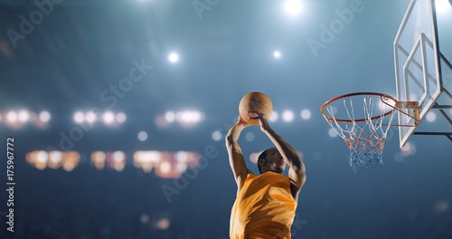 Basketball player performs a slam dunk on a sport background © haizon