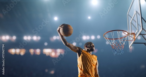 Basketball player performs a slam dunk on a sport background photo