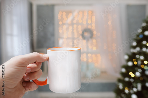 A cup with a hot drink in the hand on a background of Christmas decorations