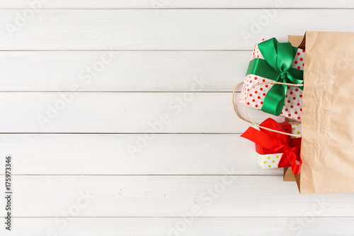 Traditional christmas gifts in paper bag on white rustic wood table background