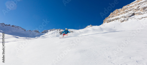 Young man snowboarder running downhill in powder snow, Alpine mountains.