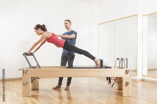 Pilates lesson on reformer, personal coaching young beautiful woman