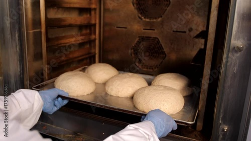Baker puts the bread in the oven